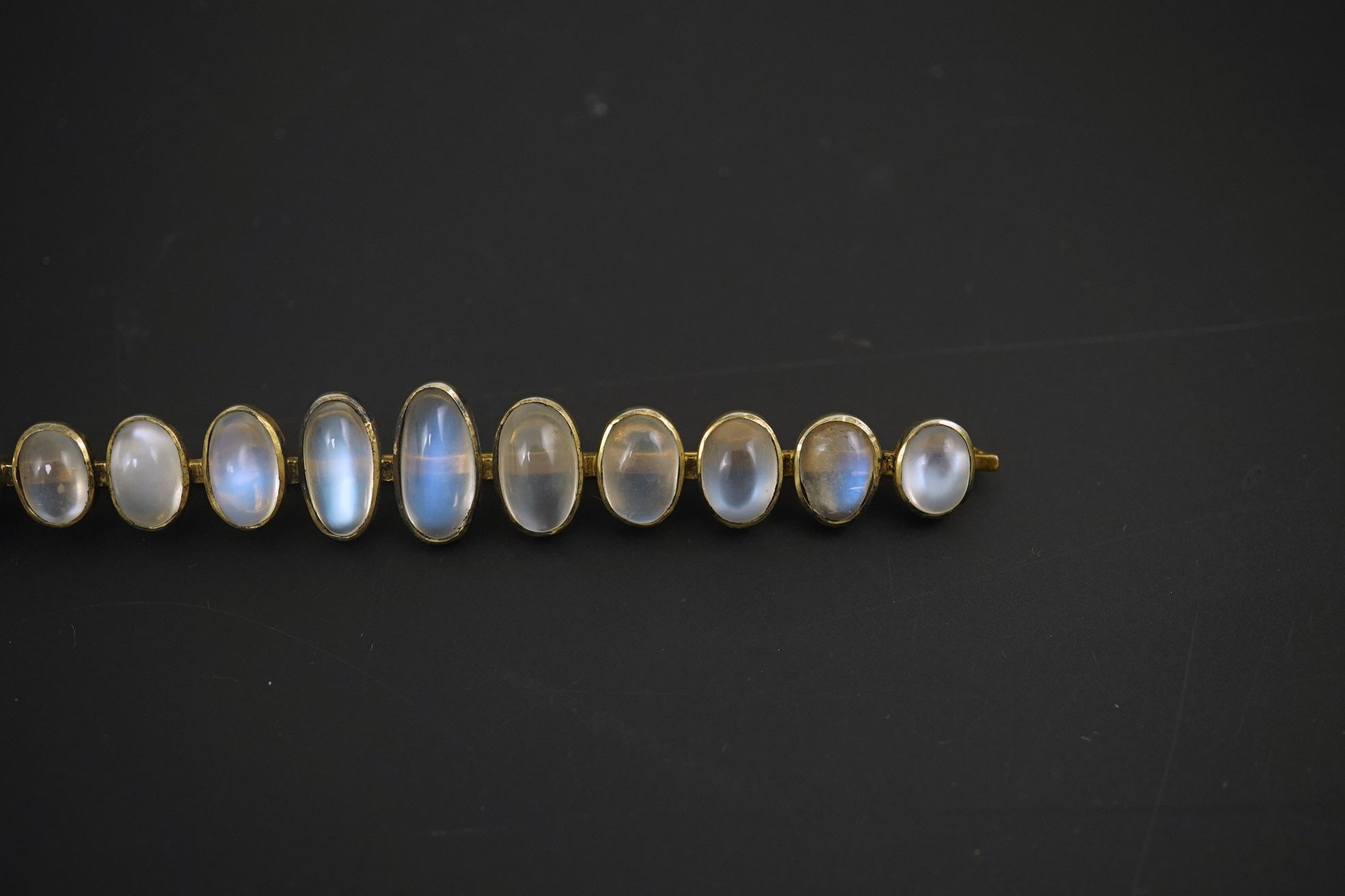 A gold and eleven stone graduated cabochon moonstone set bar brooch